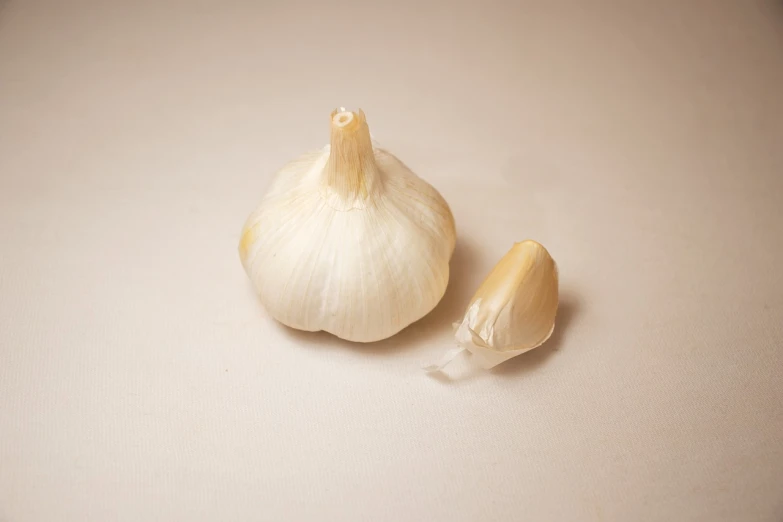 a couple of cloves of garlic on a table, by Jan Rustem, miniature product photo, white muzzle and underside, white backround, product introduction photo