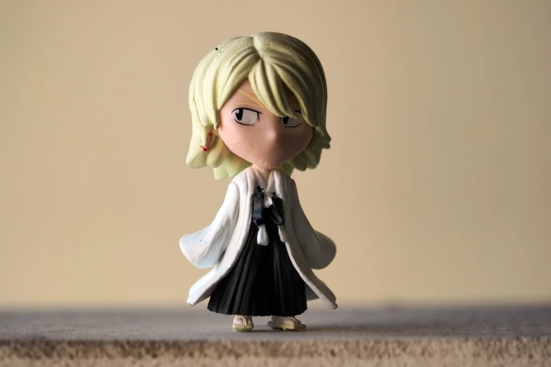 a figurine of a woman with blonde hair and glasses, inspired by Sakai Hōitsu, unsplash, in a flowing white tailcoat, sanji, wearing a black cloak, very very low quality picture