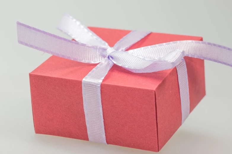 a pink gift box with a purple ribbon, by Eden Box, pixabay, red and white color theme, trimmed with a white stripe, on grey background, 25 years old