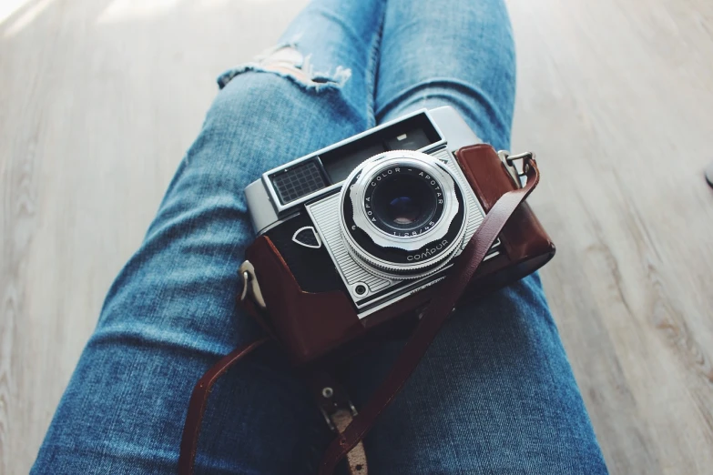 a close up of a person holding a camera, instagram contest winner, vintage camera, blue jeans, natural lighting, photography”