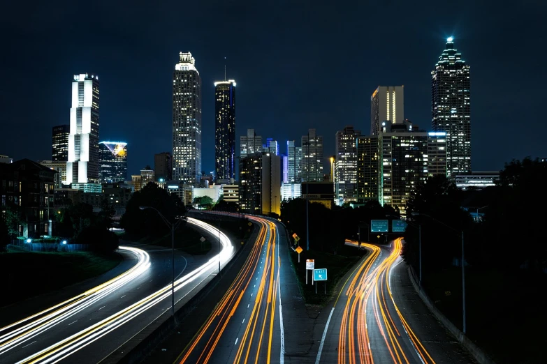 a long exposure photo of a city at night, a picture, by Andrew Domachowski, high traffic, many smooth curves, skyline showing, headlights turned on