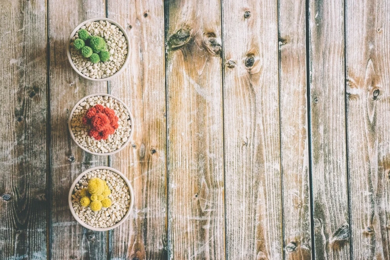 three bowls of food sitting on top of a wooden table, a stock photo, pexels, detailed colored textures, red green yellow color scheme, grainy picture, cereal