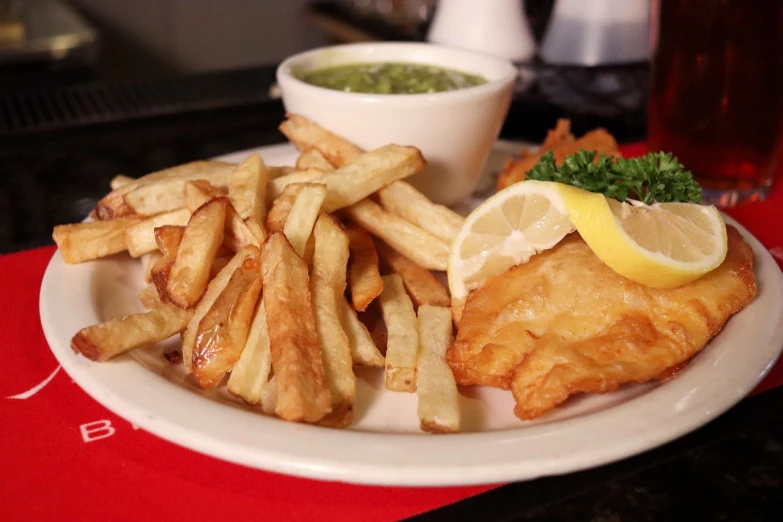 a white plate topped with french fries and a lemon wedge, renaissance, fish in the background, greenish tinge, old english, 3/4 view from below