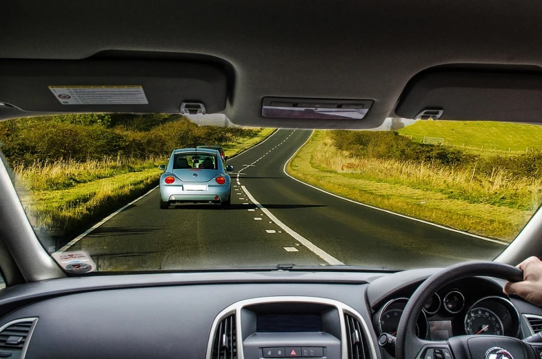 a man driving a car down a country road, a picture, by Richard Carline, pixabay, happening, rear facing, very accurate photo, full view of a car, split near the left