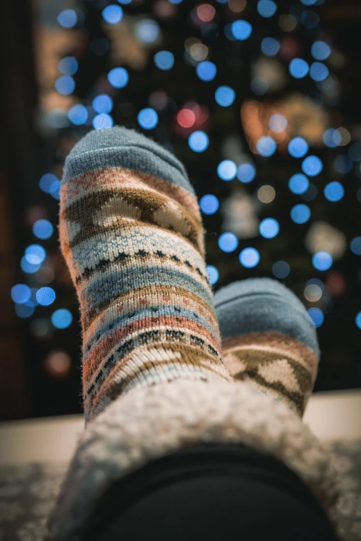 a person wearing a pair of socks with a christmas tree in the background, by Maksimilijan Vanka, pexels, realism, warm summer nights, avatar image, slippers, bokeh. i