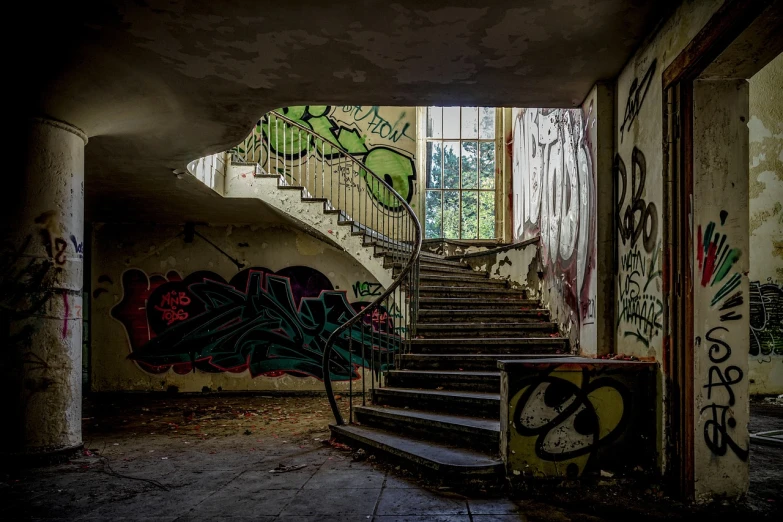 a staircase in an abandoned building with graffiti on the walls, by Sebastian Spreng, graffiti, mossy buildings, abandoned hospital, photo taken in 2018, artist unknown