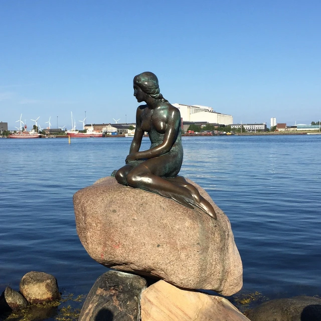 a statue of a woman sitting on top of a rock, a statue, by Christen Dalsgaard, ariel the little mermaid, looking from side!, viewed from the harbor, lone petite female goddess