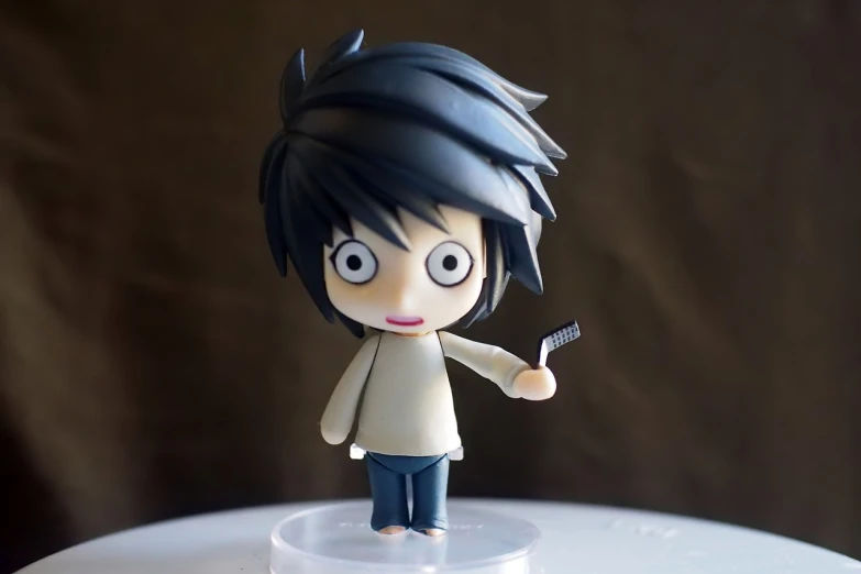 a close up of a figurine of a person holding a cell phone, inspired by Takeshi Obata, flickr, eyes in the style of nendoroid, l · lawliet, <pointé pose>;open mouth, toy commercial photo