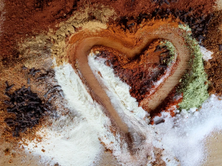 the ingredients of a heart shaped cake are mixed together, a macro photograph, inspired by János Valentiny, trending on pexels, process art, earth colors, powder, dark brown white green colours, paprika