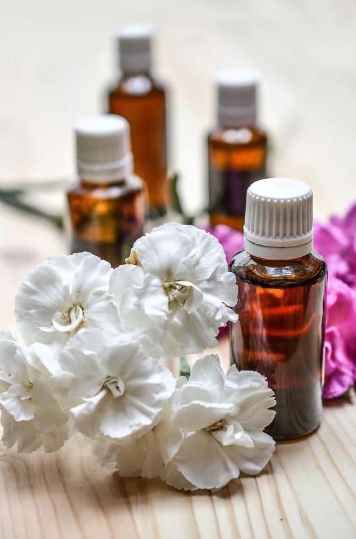 a wooden table topped with bottles of essential oils and flowers, a picture, by Rhea Carmi, pexels, brown and white color scheme, carnation, profile picture, chicago