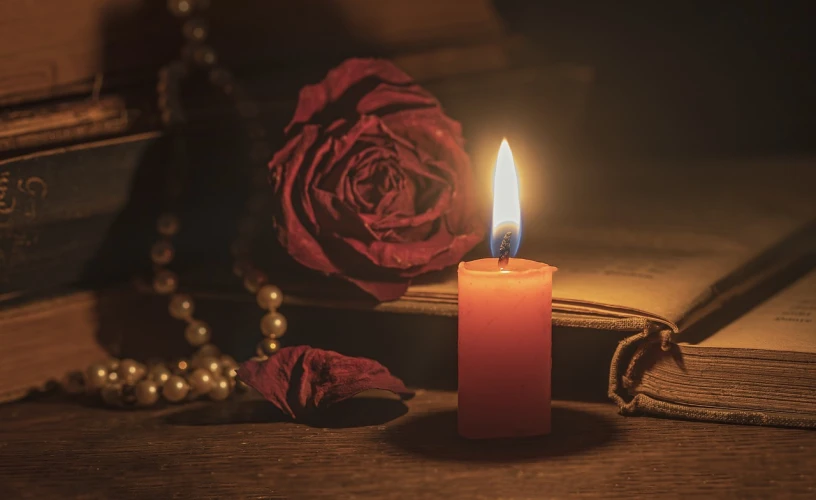 a candle sitting on top of a book next to a rose, a picture, by Romain brook, pixabay, avatar image, portrait of mournful, red and orange glow, profile picture