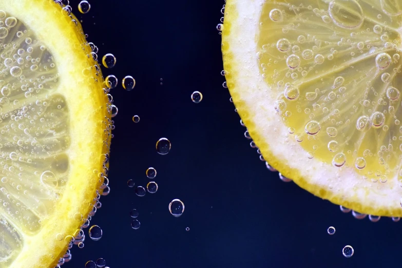 two slices of lemon sitting next to each other, a macro photograph, pexels, digital art, underwater bubbles background, fruits, banner, cold drinks