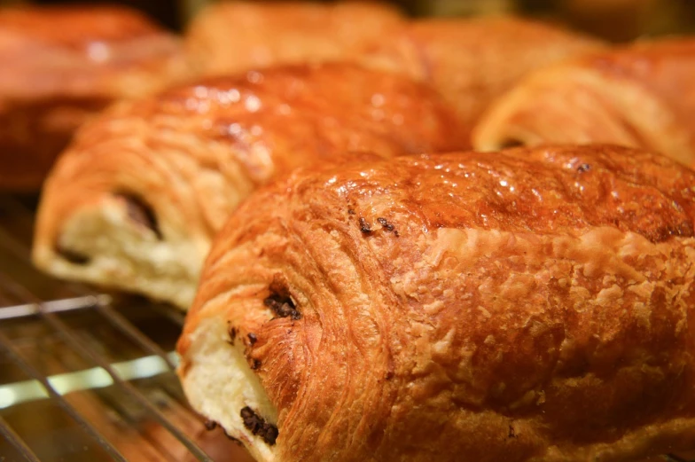 a close up of some croissants on a rack, inspired by Normand Baker, pexels, hurufiyya, chocolate, wikimedia, s line, malt