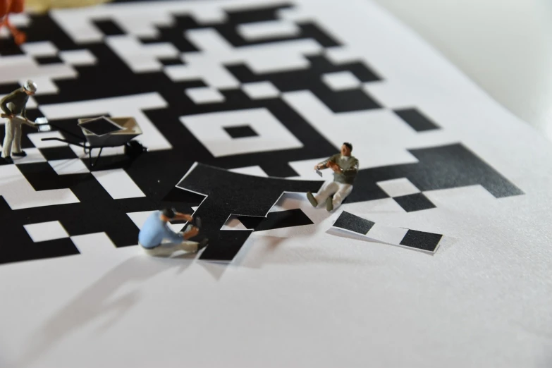 a group of figurines sitting on top of a piece of paper, a macro photograph, by Jesper Knudsen, interactive art, smartphone displays qr code, papercut, maze, miniature photography closeup