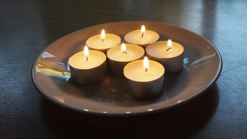 a plate with five lit candles on it, a picture, full of light, istockphoto, regular sized, ceramic