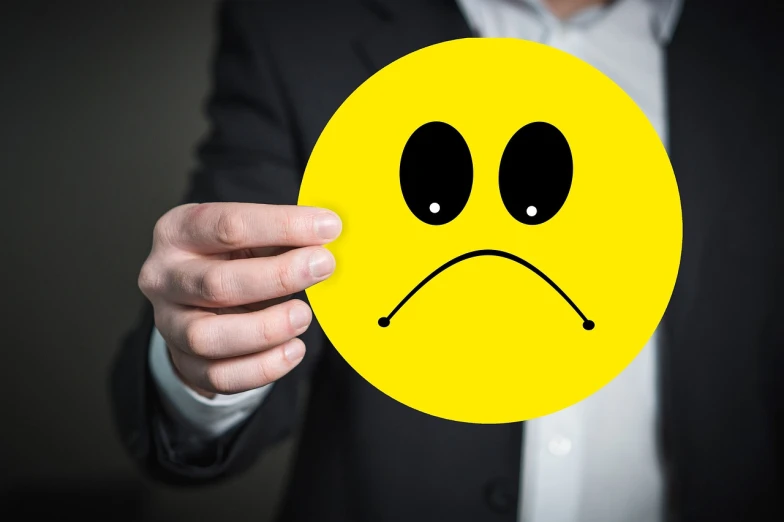 a man in a suit holding a yellow smiley face, excessivism, is totally sad and cries, bad lighting, no logo, istockphoto