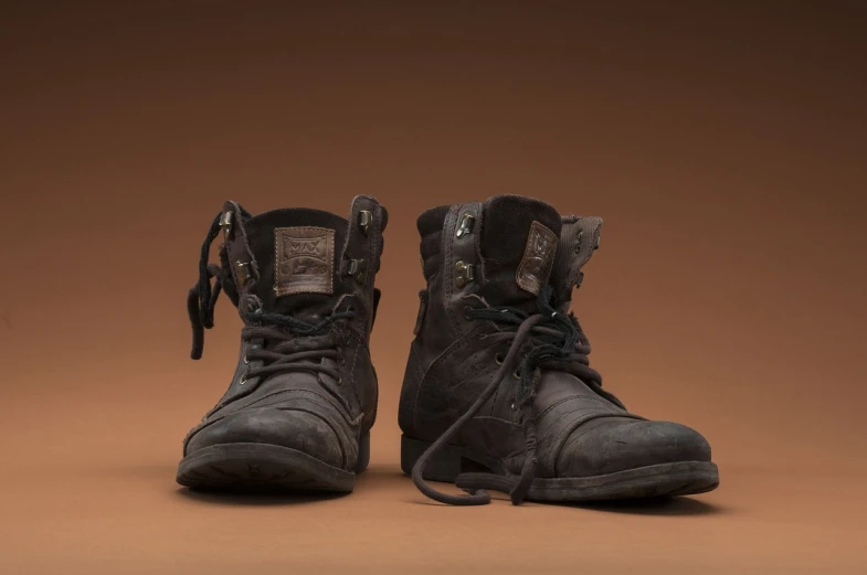 a pair of black boots sitting on top of a brown surface, by Jason Benjamin, photorealism, scale model photography, grungy, tony roberts, weta