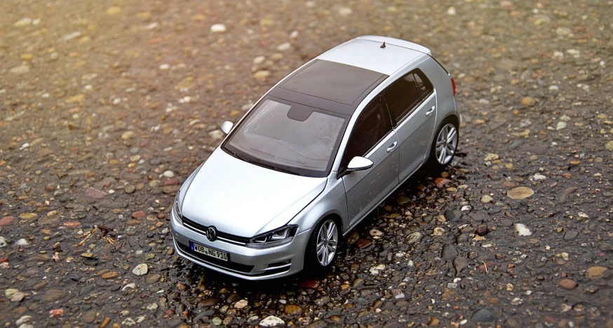 a toy car is sitting on the ground, a picture, by Hans Schwarz, pixabay, photorealism, wrx golf, grey metal body, model miniature, hillside