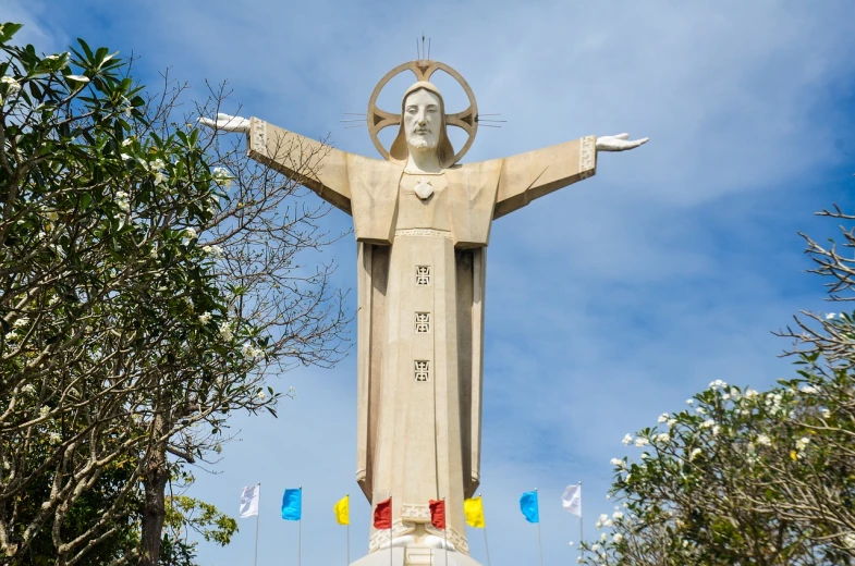 a statue of jesus in front of a blue sky, art deco, vietnam, catholic icon, high res photo, full shot photo