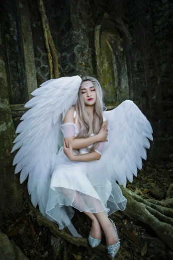 a woman dressed as an angel sitting on a rock, inspired by Anne Stokes, shutterstock, ava max, crying queen of feathers, heonhwa choe, cosplay photo