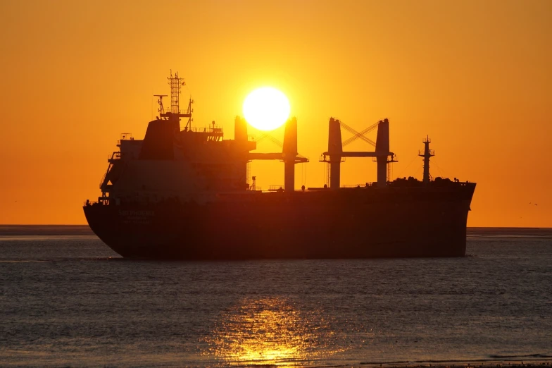 a large ship sitting on top of a body of water, a picture, by Ian Fairweather, pixabay, blocking the sun, crude, siluette, shot on 1 5 0 mm