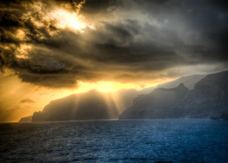 a large body of water under a cloudy sky, a picture, by Etienne Delessert, pexels contest winner, romanticism, holy rays, seas of mountain, tonemapped, golden glow