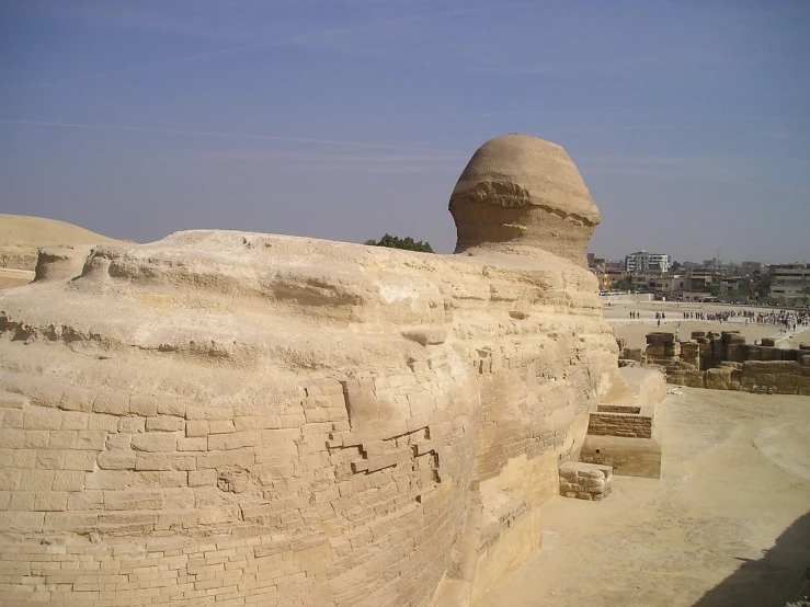 a large stone sphinx sitting on top of a sandy field, egyptian art, by Pamphilus, flickr, city wall, looking from shoulder, that resembles a bull\'s, spherical