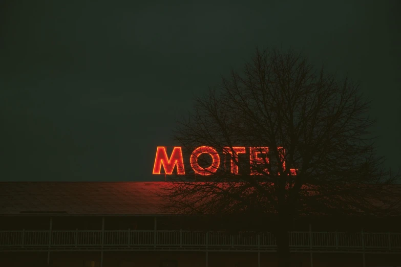 a motel sign on top of a building at night, inspired by Elsa Bleda, pexels, modernism, an example of saul leiter's work, red writing, spooky photo, artist unknown