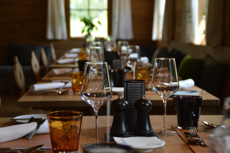 a group of wine glasses sitting on top of a wooden table, by Jaakko Mattila, pexels, dining room, western setting, diner, looking left