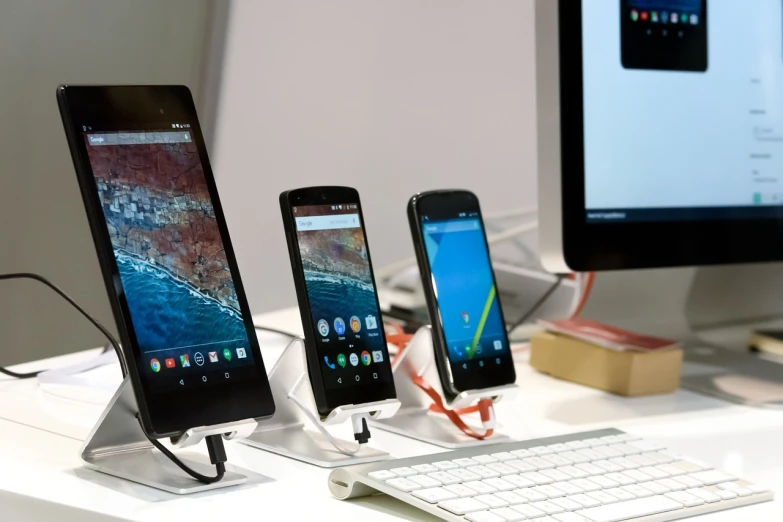 three cell phones sitting next to each other on a desk, a picture, by Matthias Stom, pexels, figuration libre, many monitors, who is a android, on display, google design