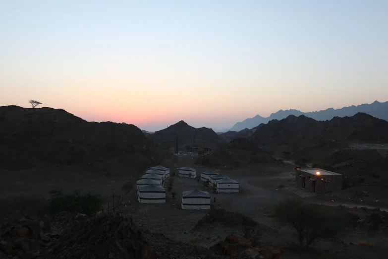 a group of buses that are sitting in the dirt, by Dietmar Damerau, flickr, hurufiyya, mountains and sunset!!, barracks, oman, huts