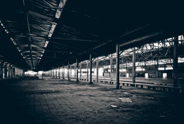 a black and white photo of a train station, a black and white photo, lost place photo, empty warehouse background, large pillars, late night melancholic photo