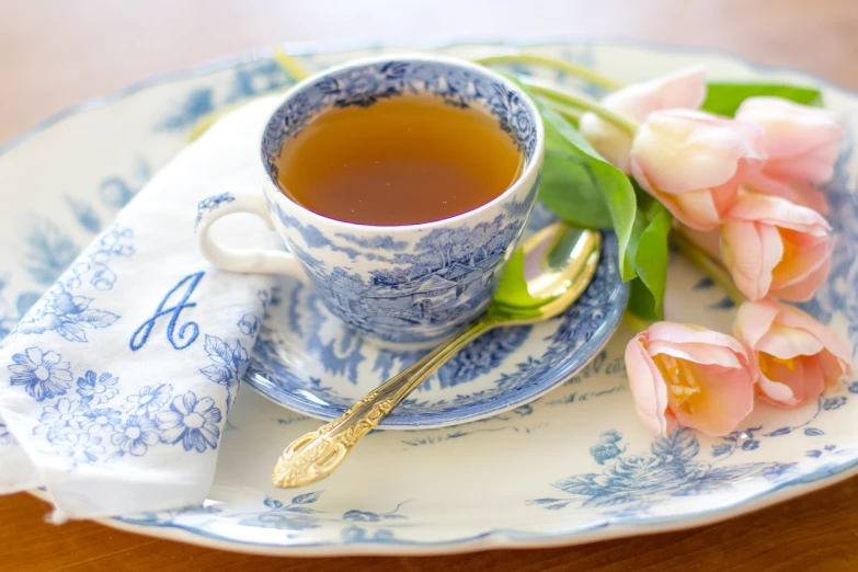 a blue and white plate topped with a cup of tea, by Mary Anne Ansley, pixabay, romanticism, tulip, blushing, assam tea garden setting, vanilla