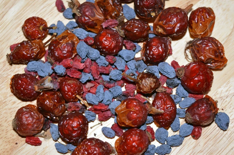 a pile of dried berries sitting on top of a wooden table, by Ella Guru, hurufiyya, cobalt blue and pyrrol red, changquan, tea, extra detail