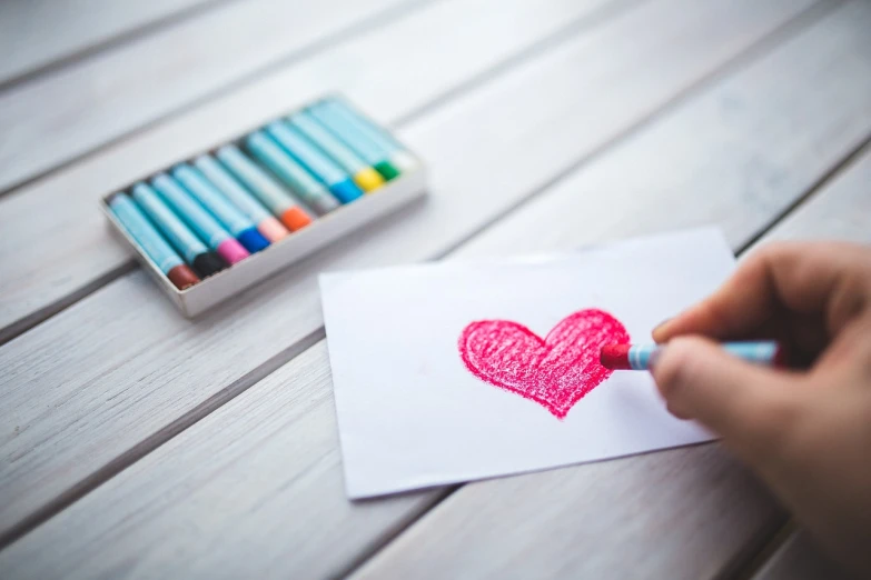 a person drawing a heart on a piece of paper, a child's drawing, by Sylvia Wishart, pexels, crayon art, card, romantic lead, uwu, chalky