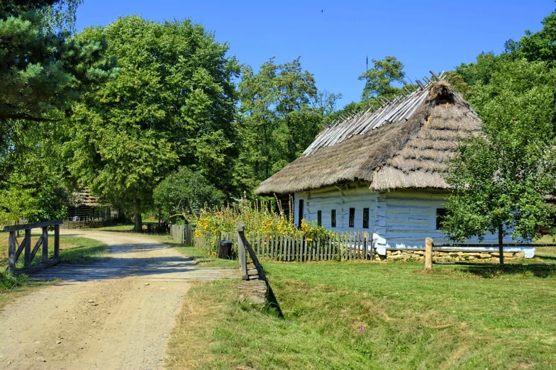 a white house with a thatched roof next to a dirt road, by György Vastagh, pixabay, folk art, ancient slavs, sunny summer day, benjamin vnuk, hideen village in the forest