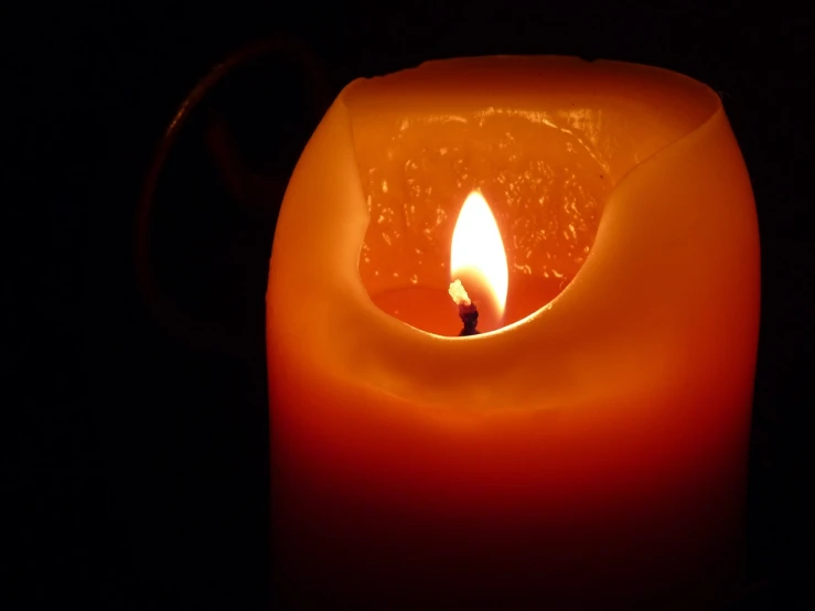 a close up of a lit candle in the dark, a picture, by Tom Carapic, realistic footage, made of glowing wax and ceramic, istockphoto, orange and red lighting