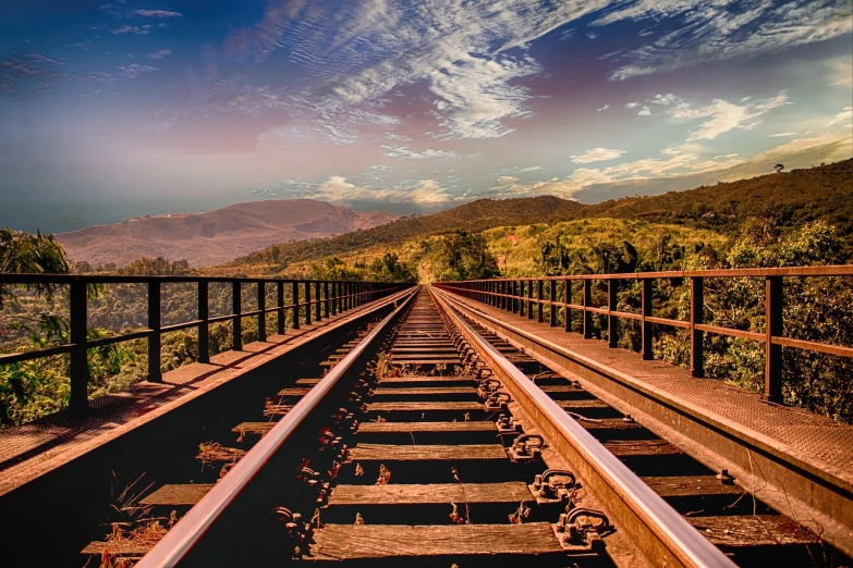 a train track with mountains in the background, a stock photo, shutterstock, romanticism, bridges and railings, leading to the sky, low angle 8k hd nature photo, wide high angle view