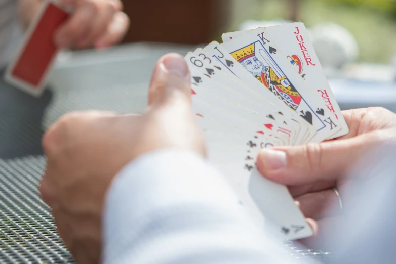 a close up of a person holding playing cards, a screenshot, by Jason Felix, pexels, instagram post, facing off in a duel, shot on 1 5 0 mm, easy to use