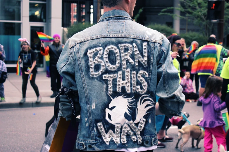 a man wearing a denim jacket that says born this way, featured on tumblr, a unicorn, view from the streets, sparkly, gritty!!!