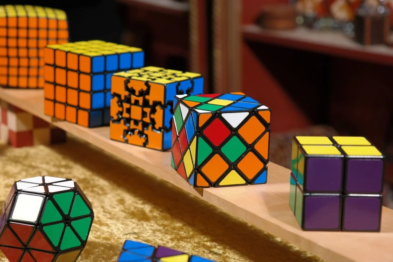 a group of rubik cubes sitting on top of a wooden shelf, a jigsaw puzzle, video still, nbc, lattice, r - mk