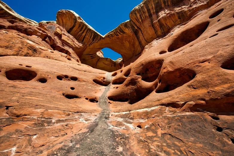 a large rock formation with holes in it, by Don Reichert, shutterstock, an archway, wide angle landscape photography, details and vivid colors, utah