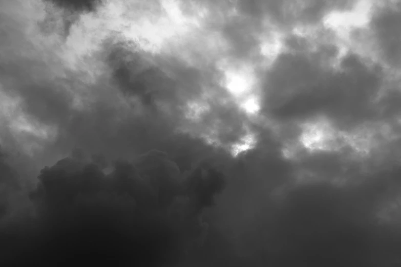 a black and white photo of a cloudy sky, a black and white photo, colorfully ominous background, surrounded in clouds and light, menacing, obscured underexposed view