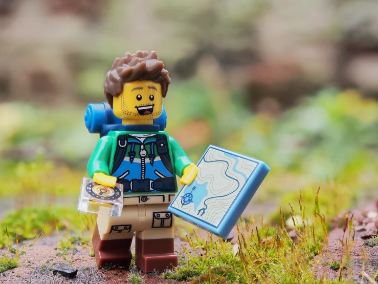 a close up of a lego figure holding a map, a picture, by Jesper Knudsen, pexels, trekking in a forest, with a happy expression, diego 5, casually dressed