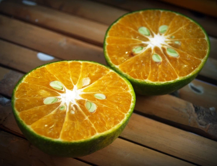 two halves of an orange on a wooden table, by Jan Tengnagel, pexels, shin hanga, lime green, mottled coloring, designed in blender, view from bottom to top