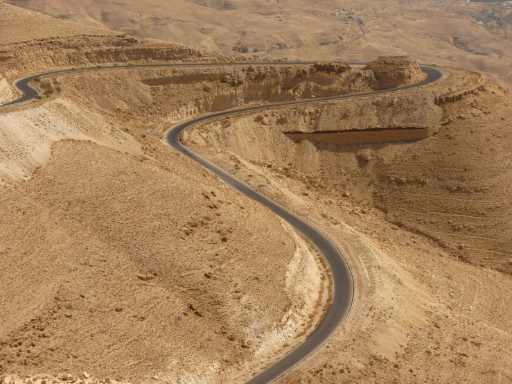 an aerial view of a winding road in the desert, by Israel Tsvaygenbaum, in between a gorge, wide screen, high res photo, side