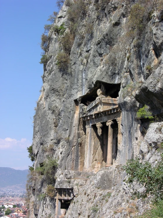 a building built into the side of a cliff, by Muggur, flickr, some marble statues can be seen, in an ancient tomb, stern like athena, ancient”