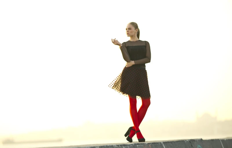 a woman in a black dress and red tights, romanticism, standing on rooftop, full body backlight, taken with canon eos 5 d, polka dot