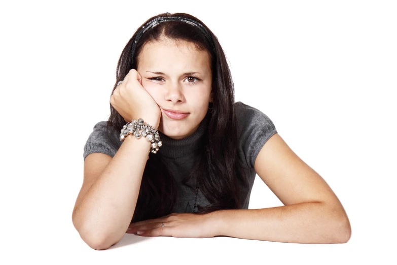 a woman sitting at a table with her hand on her chin, a picture, teenager girl, istockphoto, struggle, set against a white background