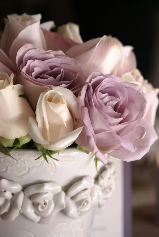 a close up of flowers in a vase on a table, romanticism, light purple, white roses, ceramic, cake